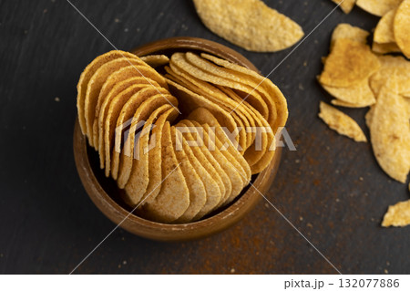 potato chips fried in oil and sprinkled with dried red sweet pepper, a large number of delicious salty chips with aromatic spices potato chips fried in oil and sprinkled with dried red sweet pepper, a large number of delicious salty chips with aromatic spices 132077886