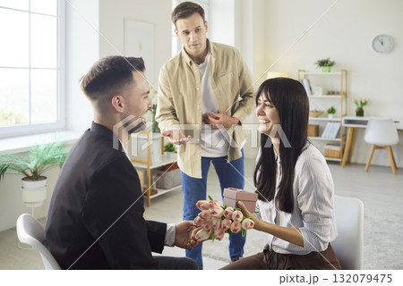 Woman with bouquet and gift as man proposes while another man looks surprised 132079475
