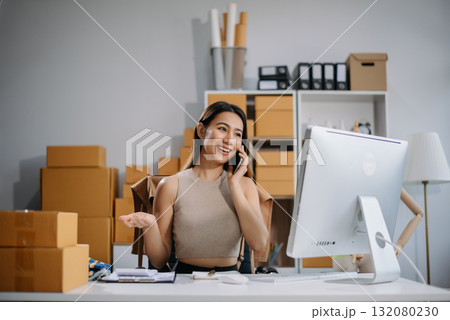 Asian woman prepares parcels and checks online orders on tablet and laptop for delivery online shopping and small business success Asian woman prepares parcels and checks online orders on tablet and laptop for delivery online shopping and small business success 132080230