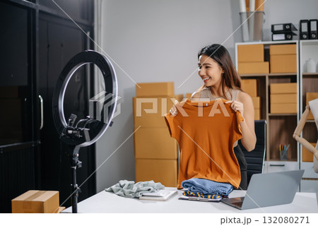 Asian woman prepares parcels and checks online orders on tablet and laptop for delivery online shopping and small business success Asian woman prepares parcels and checks online orders on tablet and laptop for delivery online shopping and small business success 132080271