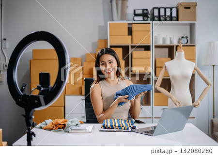 Asian woman prepares parcels and checks online orders on tablet and laptop for delivery online shopping and small business success 132080280
