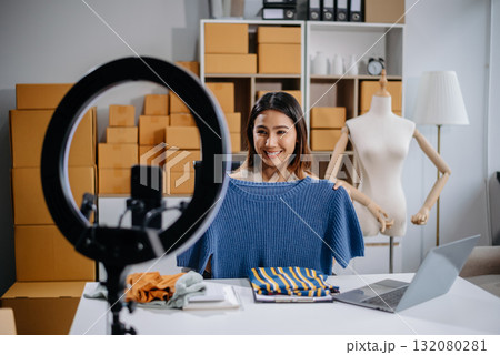 Asian woman prepares parcels and checks online orders on tablet and laptop for delivery online shopping and small business success 132080281