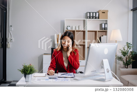 Young beautiful woman typing on tablet and laptop while sitting at the working white table in modern office Young beautiful woman typing on tablet and laptop while sitting at the working white table in modern office 132080308