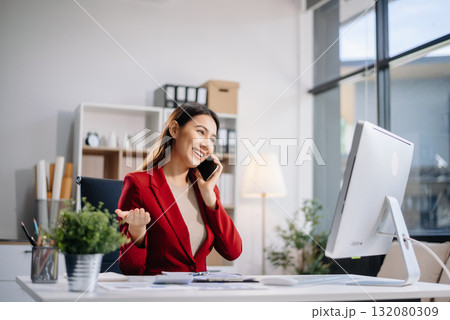 Young beautiful woman typing on tablet and laptop while sitting at the working white table in modern office 132080309