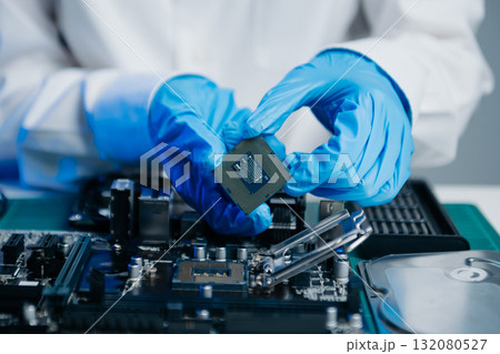 The technician is putting the CPU on the socket of the computer motherboard. electronic engineering electronic repair, 132080527