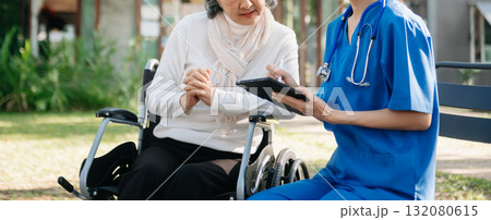 Elderly asian senior woman on wheelchair with Asian careful caregiver and encourage patient, walking in garden. 132080615