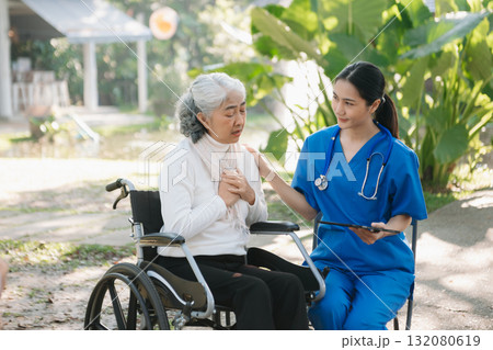 Elderly asian senior woman on wheelchair with Asian careful caregiver and encourage patient, walking in garden. Elderly asian senior woman on wheelchair with Asian careful caregiver and encourage patient, walking in garden. 132080619