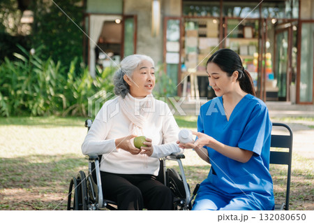 Asian young caregiver nurse support senior older male walking outdoors. Specialis doctor help and take care of elderly mature. Asian young caregiver nurse support senior older male walking outdoors. Specialis doctor help and take care of elderly mature. 132080650