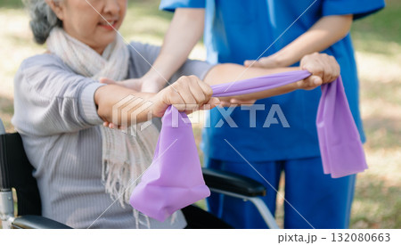 Asian physiotherapist helping elderly woman patient stretching arm during exercise correct with dumbbell in hand during training hand with patient Back problems in the garden. Asian physiotherapist helping elderly woman patient stretching arm during exercise correct with dumbbell in hand during training hand with patient Back problems in the garden. 132080663
