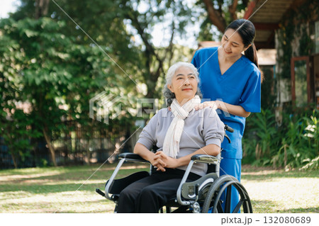 Asian physiotherapist helping elderly woman patient stretching arm during exercise correct with dumbbell in hand during training hand with patient Back problems in the garden. 132080689