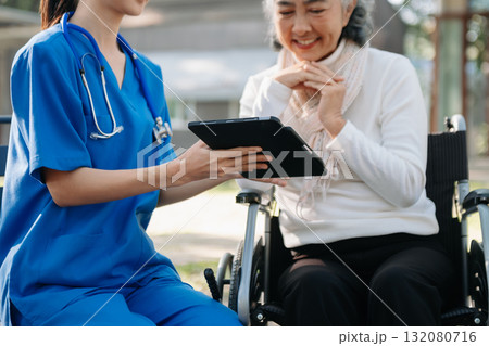 Elderly asian senior woman on wheelchair with Asian careful caregiver and encourage patient, walking in garden. Elderly asian senior woman on wheelchair with Asian careful caregiver and encourage patient, walking in garden. 132080716