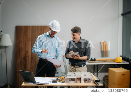 Two colleagues discussing data working and tablet, laptop with architectural project at construction site Two colleagues discussing data working and tablet, laptop with architectural project at construction site 132080766