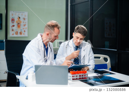 Diverse team of doctors and specialists brainstorming with digital tools, discussing test results and planning in hospital Diverse team of doctors and specialists brainstorming with digital tools, discussing test results and planning in hospital 132080886