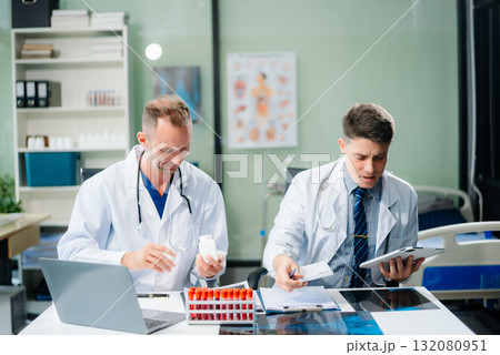 Diverse team of doctors and specialists brainstorming with digital tools, discussing test results and planning in hospital Diverse team of doctors and specialists brainstorming with digital tools, discussing test results and planning in hospital 132080951