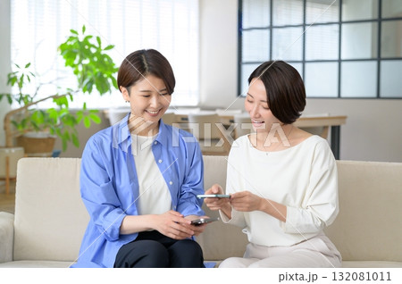 ソファに座ってスマホをかざす日本人女性 132081011