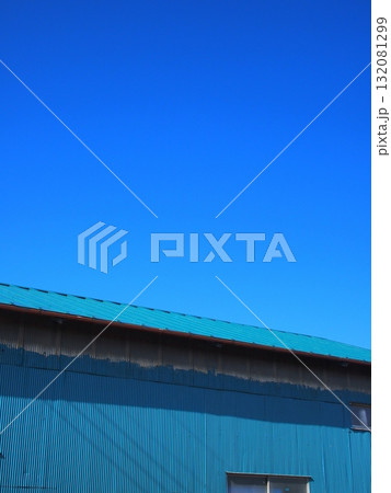 冬の畑の中のトタン壁の物置小屋と青空 132081299