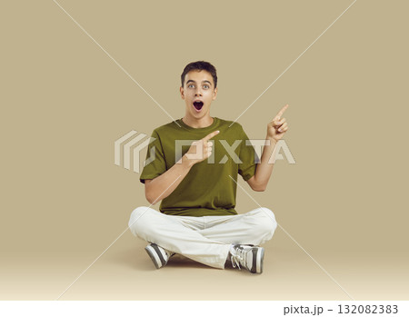 Cheerful amazed teenager boy showing on copy space for idea of promotional product or text. Cheerful amazed teenager boy showing on copy space for idea of promotional product or text. 132082383