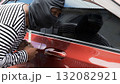 Masked thief breaking into a car using metal tool, concept of crime, car theft, danger, and security risk. Symbol of illegal activity, vehicle protection awareness 132082921
