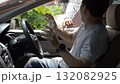 Masked thief threatening a driver through a car window during an attempted robbery. Concept of car crime, carjacking, danger, security awareness, and personal safety in urban environments 132082925