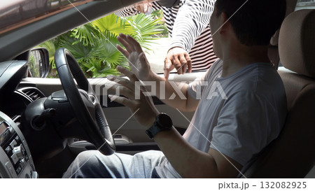 Masked thief threatening a driver through a car window during an attempted robbery. Concept of car crime, carjacking, danger, security awareness, and personal safety in urban environments Masked thief threatening a driver through a car window during an attempted robbery. Concept of car crime, carjacking, danger, security awareness, and personal safety in urban environments 132082925