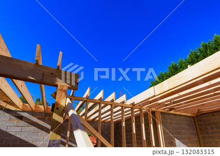 Construction workers frame wooden roof structure on building site with rafters structure beams 132083315