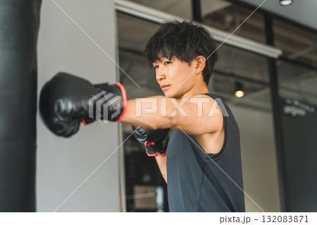 ジム,トレーニングジムでサンドバックをパンチする若いアジア人男性 132083871