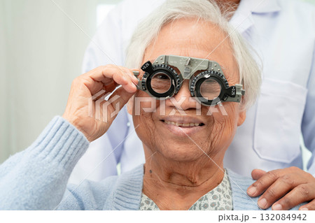 Optometrist checking Asian elderly woman ophthalmic vision eye test and using optical trial frame. 132084942
