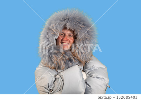 Woman in Winter Coat Points to Copy Space With a Smile on a Blue Background Woman in Winter Coat Points to Copy Space With a Smile on a Blue Background 132085403