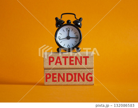 Patent Pending symbol. Wooden blocks with words Patent Pending. Beautiful orange background with alarm clock. Business and Patent Pending concept. Copy space. Patent Pending symbol. Wooden blocks with words Patent Pending. Beautiful orange background with alarm clock. Business and Patent Pending concept. Copy space. 132086583