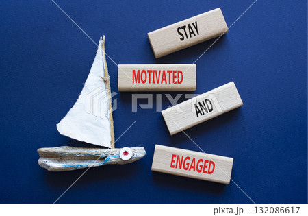 Stay Motivated and Engaged symbol. Concept words Stay Motivated and Engaged on wooden blocks. Beautiful deep blue background with boat. Business concept. Copy space 132086617