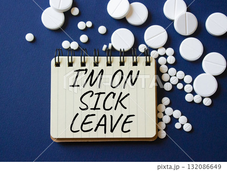 Sick leave symbol. Concept word I am on sick leave on notebook. Beautiful deep blue background with pills. Medicine and I am on sick leave concept. Copy space 132086649