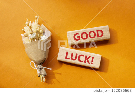 Good luck symbol. Wooden blocks with words Good luck. Beautiful orange background with bouquet of flowers. Business and Good luck concept. Copy space. Good luck symbol. Wooden blocks with words Good luck. Beautiful orange background with bouquet of flowers. Business and Good luck concept. Copy space. 132086668