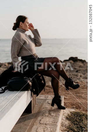 Woman Ocean Bench Outfit: Coastal Fall Fashion, Relaxed Pose, Seascape View. Woman Ocean Bench Outfit: Coastal Fall Fashion, Relaxed Pose, Seascape View. 132087045