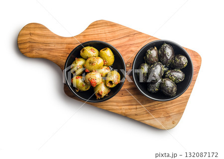 Tapas. Flavored pickled olives in bowl on cutting board isolated on white background. Tapas. Flavored pickled olives in bowl on cutting board isolated on white background. 132087172