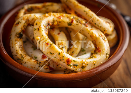 Marinated squid rings in bowl on wooden table. Marinated squid rings in bowl on wooden table. 132087240