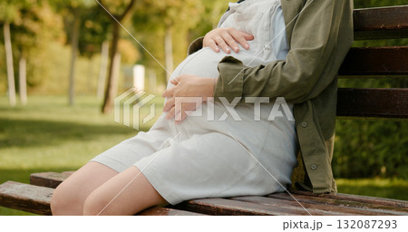 Woman carrying a baby sitting on a bench in the park. 132087293