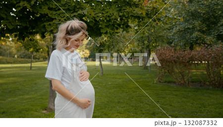 Pregnant girl woman in park touching belly and smiling. 132087332