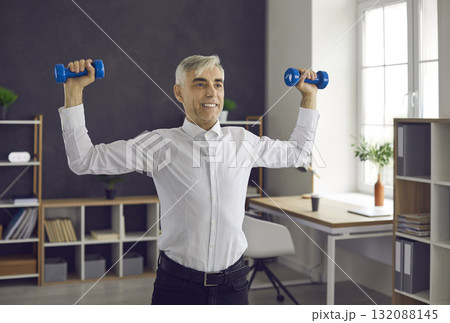 Happy senior worker doing fitness exercise during working day in office workplace 132088145