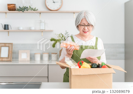 家のキッチンでミールキット,料理キットで料理をするシニア・高齢者女性（笑顔） 132089079