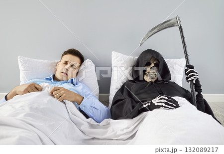 Man is fast asleep, unaware of presence of Grim Reaper, who is lying with scythe in bed next to him. Man is fast asleep, unaware of presence of Grim Reaper, who is lying with scythe in bed next to him. 132089217