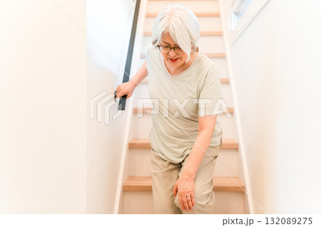自宅の階段を降りる膝を痛がるシニア女性 132089275