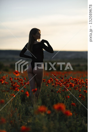 Poppy field woman sunset: Model poses among red flowers at dusk for artistic outdoor summer portrait. 132089678