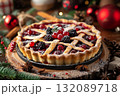 Delicious berry pie with a golden crust, garnished with fresh berries, placed on a rustic wooden table surrounded by festive decorations and holiday ambiance 132089718