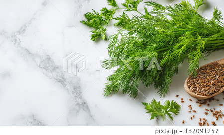 A bright image showcasing a lush bunch of fresh green dill and flax seeds spilled from a small wooden spoon, all set against a beautiful white marble background. Perfect for themes related to cooking A bright image showcasing a lush bunch of fresh green dill and flax seeds spilled from a small wooden spoon, all set against a beautiful white marble background. Perfect for themes related to cooking 132091257