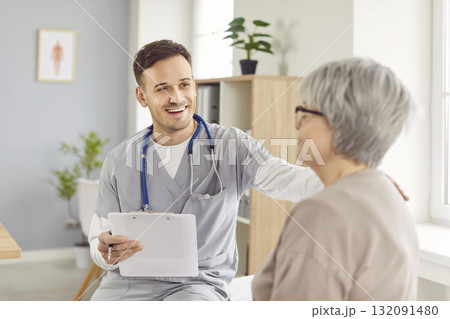 Young happy doctor, male nurse and old woman talking, supportive hand, taking social care 132091480