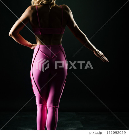 athletic female body in pink sportswear on dark background, fitness woman, athletic girl torso 132092029