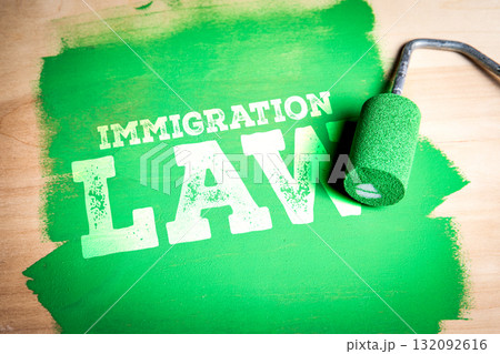 Immigration Law. Paint roller covering wooden surface in green and text immigration law appearing Immigration Law. Paint roller covering wooden surface in green and text immigration law appearing 132092616