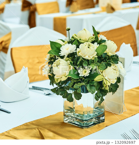 Elegant floral centerpiece with white roses on table with gold accents 132092697
