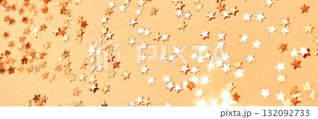 Sparkling gold star confetti scattered on orange background for festive Sparkling gold star confetti scattered on orange background for festive 132092733