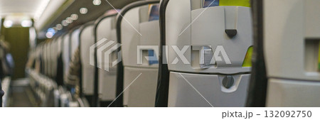 Empty airplane cabin interior with rows of seats and overhead compartments 132092750